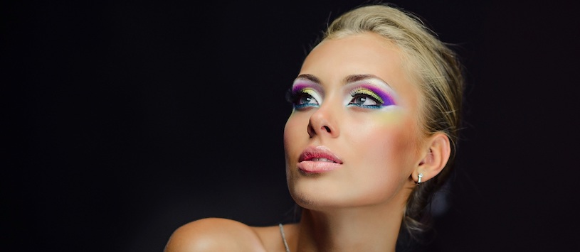 Woman wearing vibrant makeup looking into the distance.