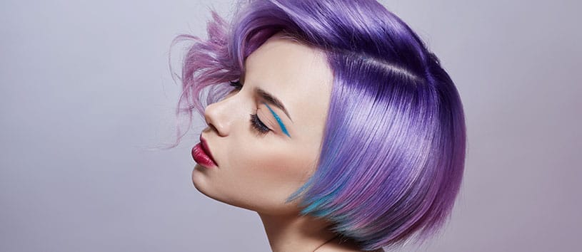 Side profile of a woman with short, purple/blue hair.