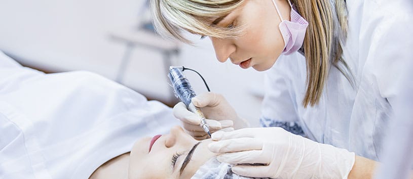 Permanent makeup treatment being done to a woman's eyebrows.