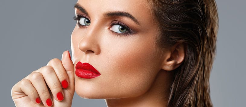 Woman with red lipstick, red nails, and slicked back hair.