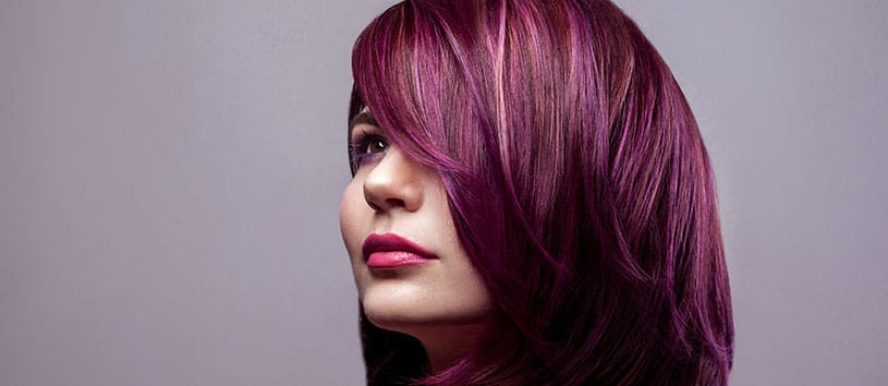 Woman with short purple hair against a purple background.