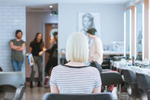 Woman with blonde hair sitting in a salon chair.